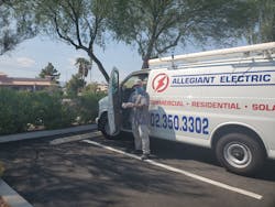 A masked employee of Allegiant Electric LLC, Las Vegas, gloves up before heading to a job site in a company vehicle.