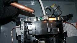 The grounded conductor (white) is terminated in the panelboard on the grounded busbar. The green screw is the main bonding jumper connecting the grounded busbar to the enclosure. A threaded hub (upper right) provides secure bonding to metal enclosures. The smaller bare copper conductor on the left is the equipment grounding conductor providing bonding. The larger bare copper on the right is the grounding electrode conductor that connects the grounded busbar to the grounding electrode system (i.e., the ground rod held in the upper left).